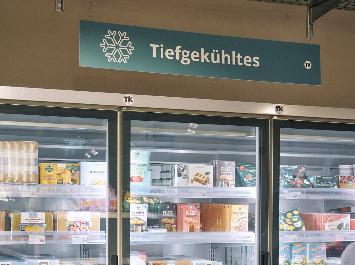 Tiefkühlregal im MILA Mitmach-Supermarkt mit Inhalt und Beschriftung darüber.